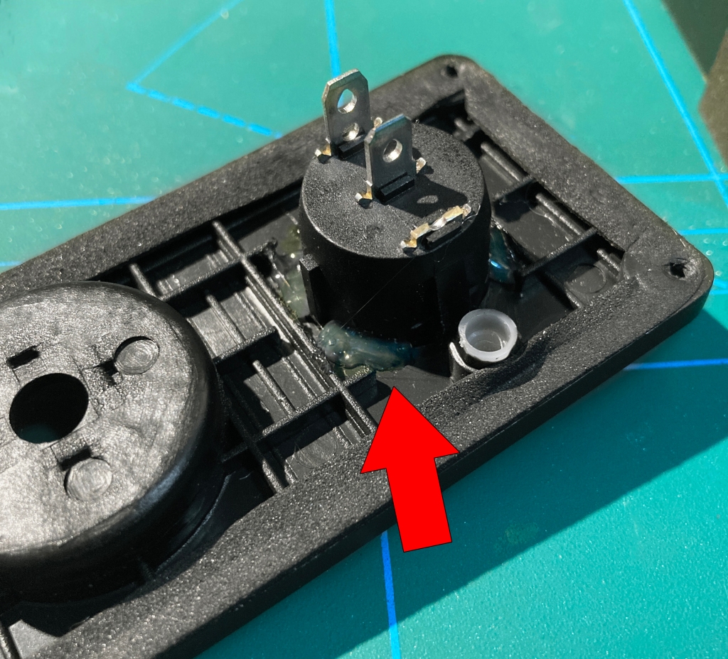 Se muestra el adhesivo termofundible aplicado al contorno del interruptor por la parte posterior del panel en que está alojado